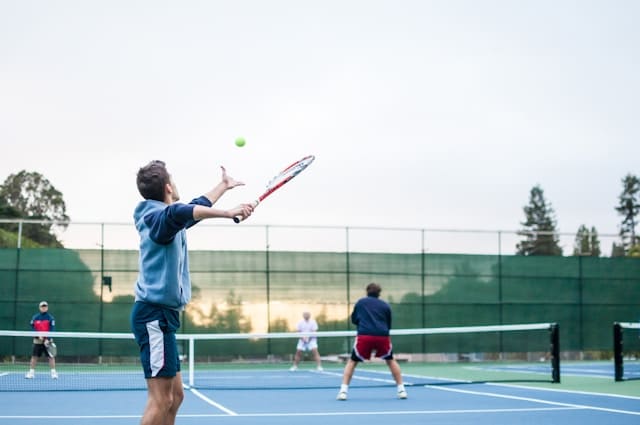 Erwachsene beim Gruppentraining auf dem Tennisplatz
